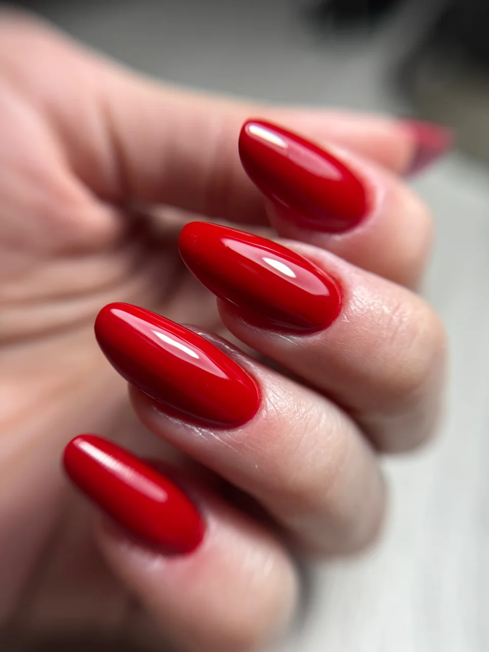 Czerwony manicure o migdałowym kształcie i lśniącym wykończeniu